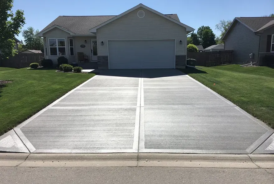 Freshly finished brushed concrete driveway attached to a two-car garage on a modest home in Baxter, Minnesota