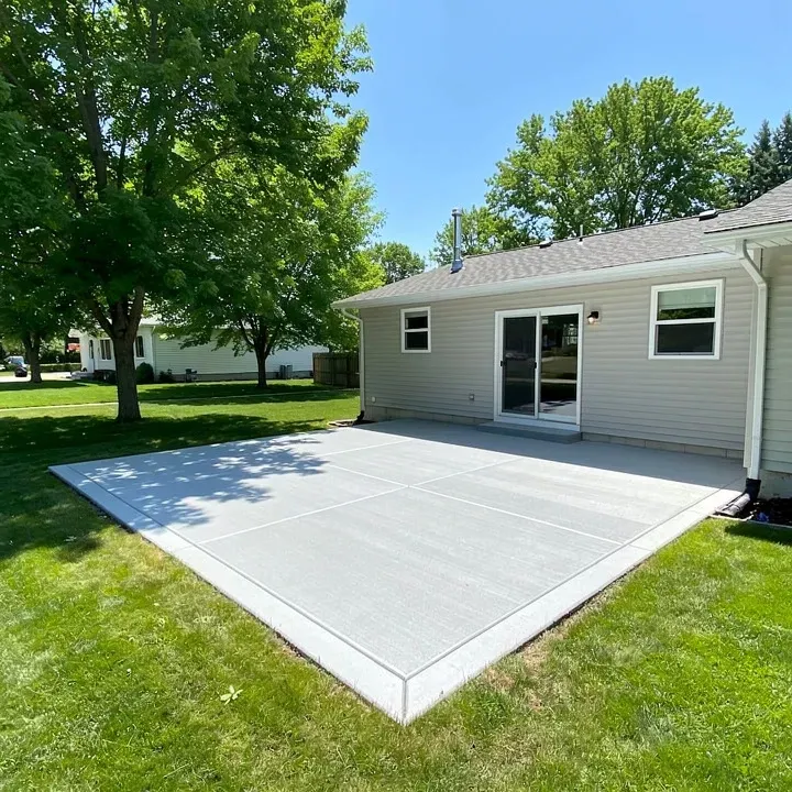 Freshly finished concrete patio attached to a modest home surrounded by mature trees in Baxter, Minnesota