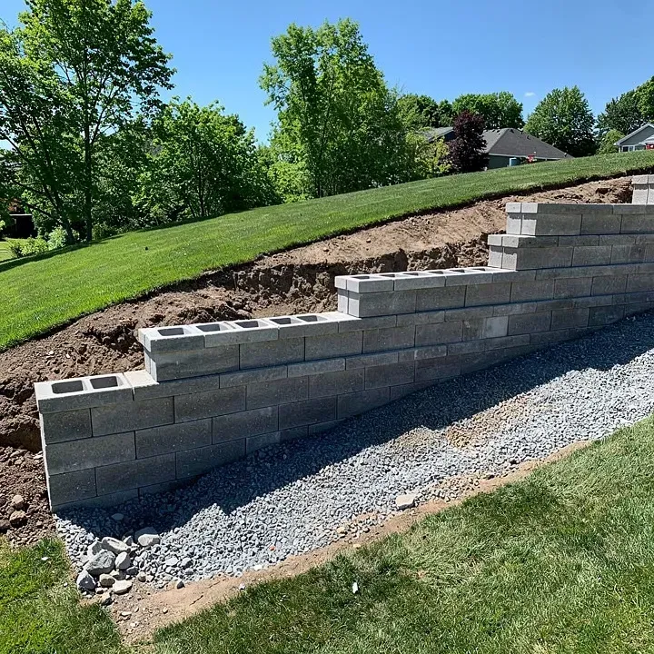 Concrete block retaining wall under construction along a sloped residential yard in Baxter, Minnesota