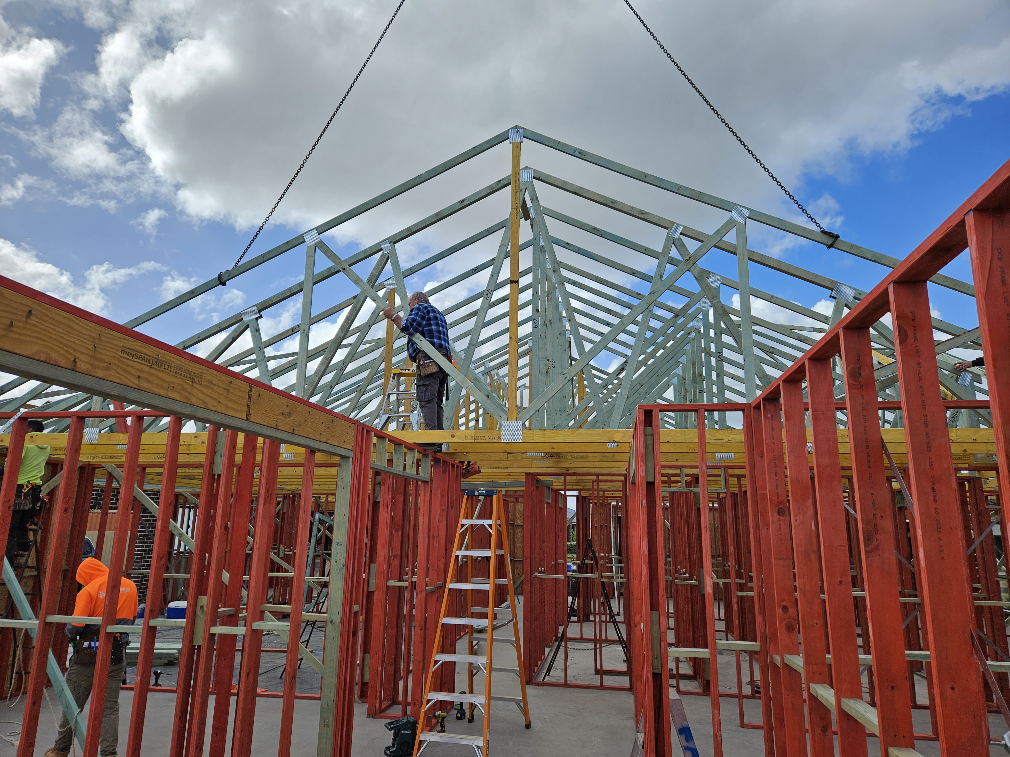 Team of carpenters constructing a timber frame house on an Australian residential building site, installing structural beams and roof trusses.
