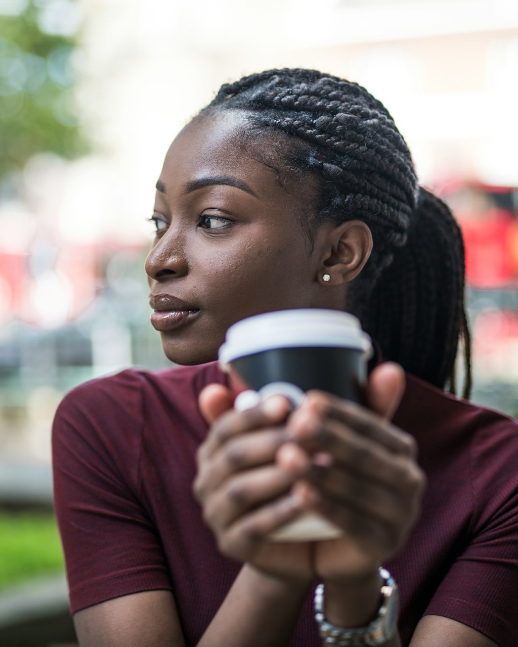 Woman holding a coffee cup and looking thoughtfully into the distance