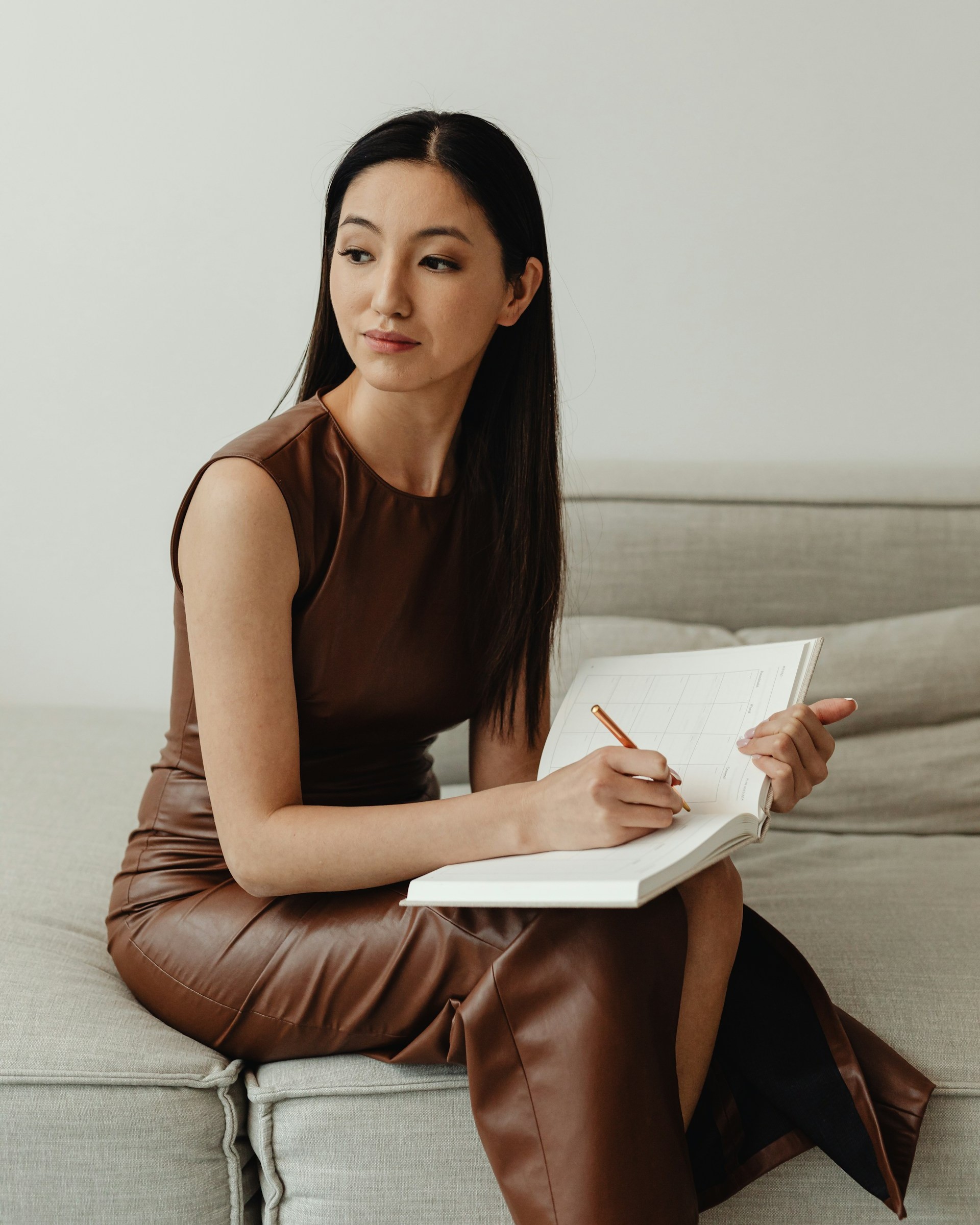 Woman writing in a notebook on sofa