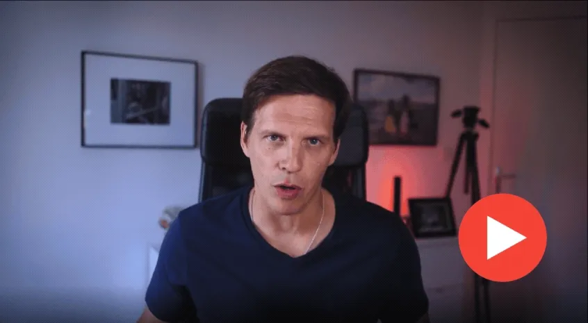 Video thumbnail of a man talking to the camera in a room, with a red play button overlaid.