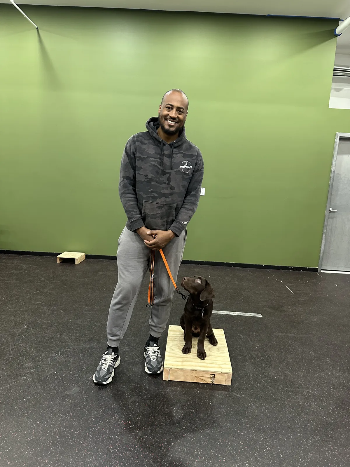 Twahlee, founder of Metro Dog Training, standing with disciplined composure in a high-contrast architectural setting in New York City