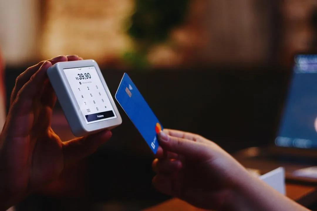 A card being held near a tap to pay reader.