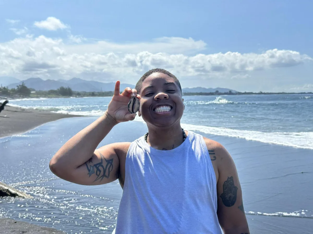 Destinē The Leader with a shell in hand at the beach in Bali, Indonesia
