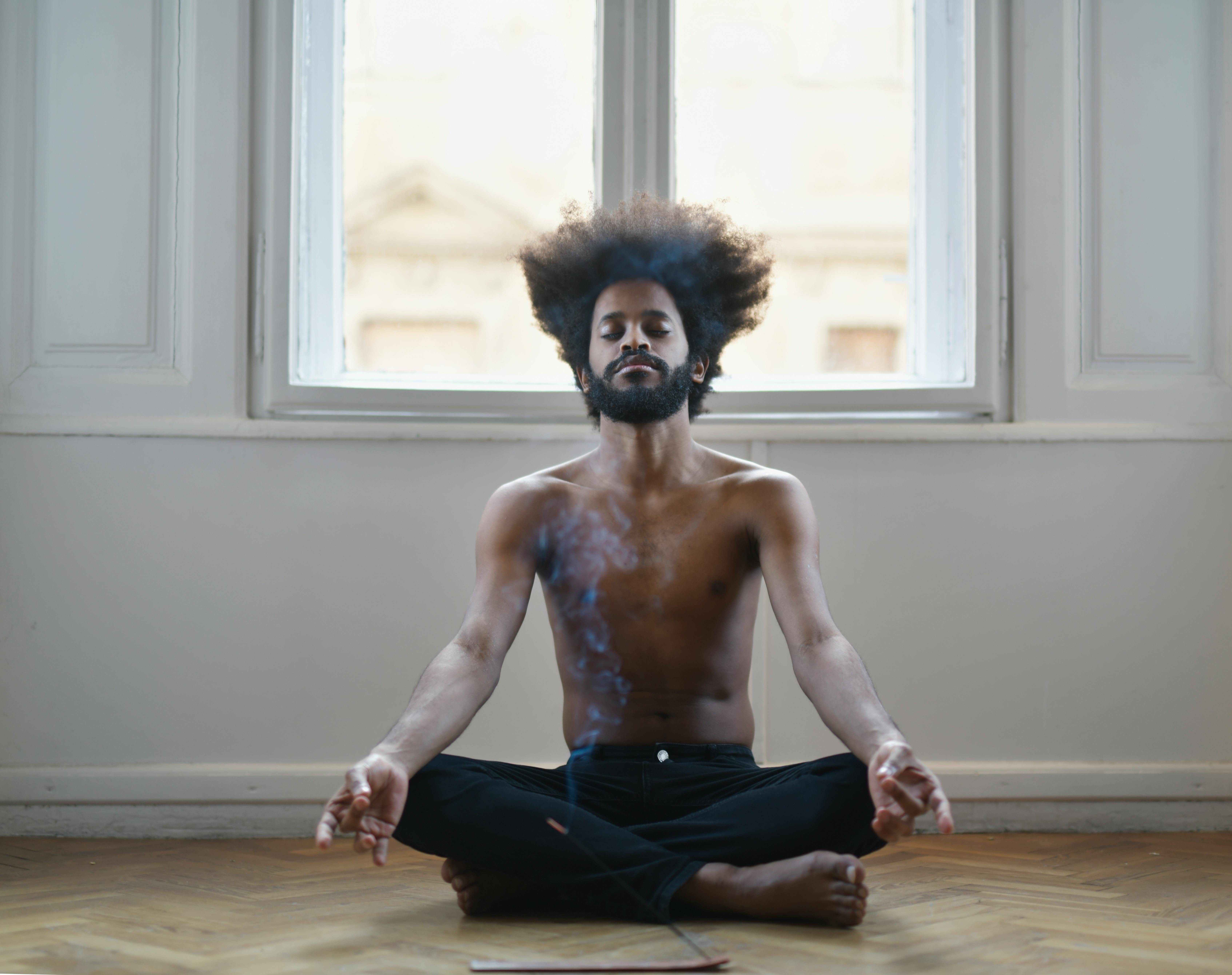 Topless Man In Black Pants Sitting On Brown Wooden Floor