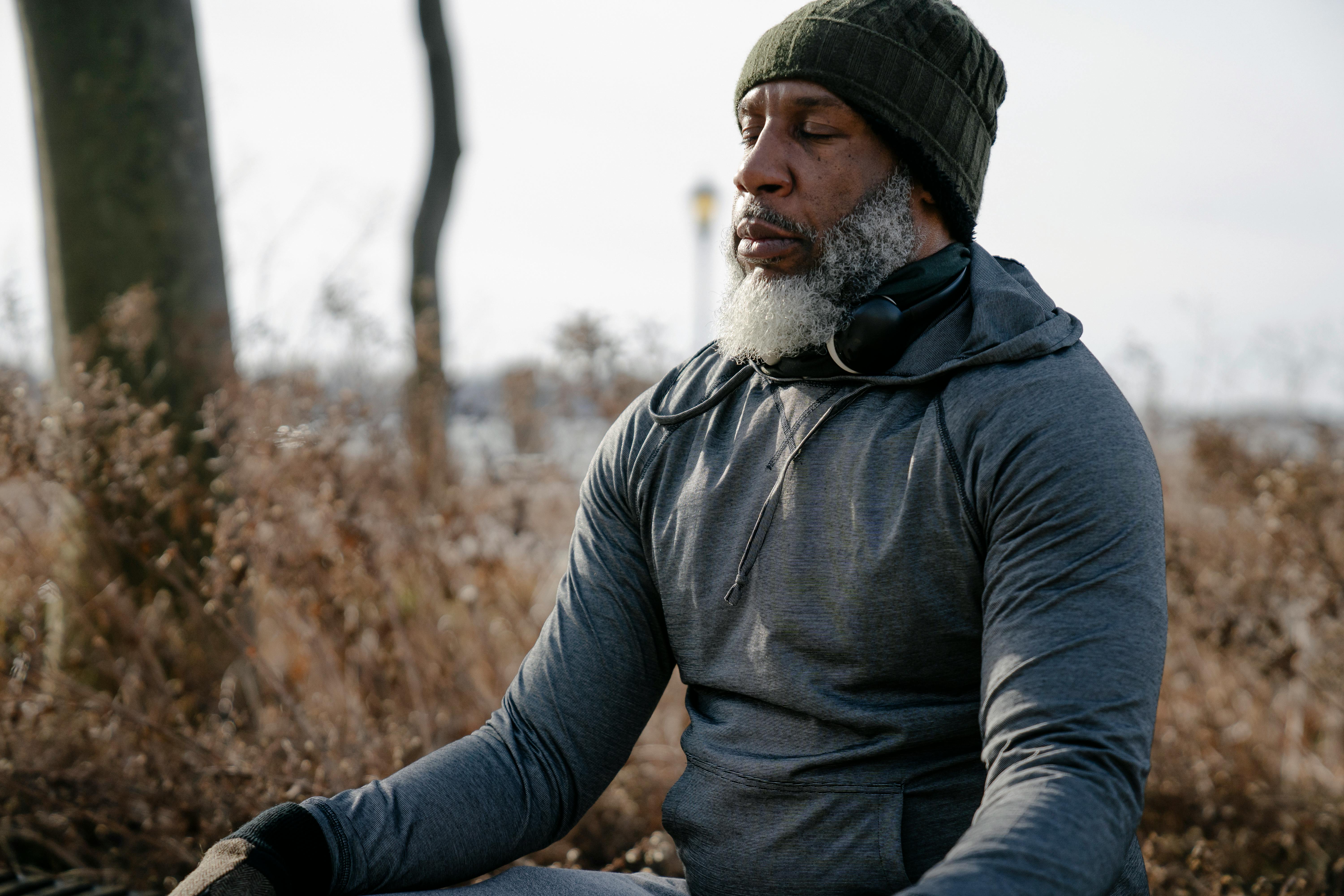 A man in activewear meditates peacefully outdoors in a serene autumn setting.