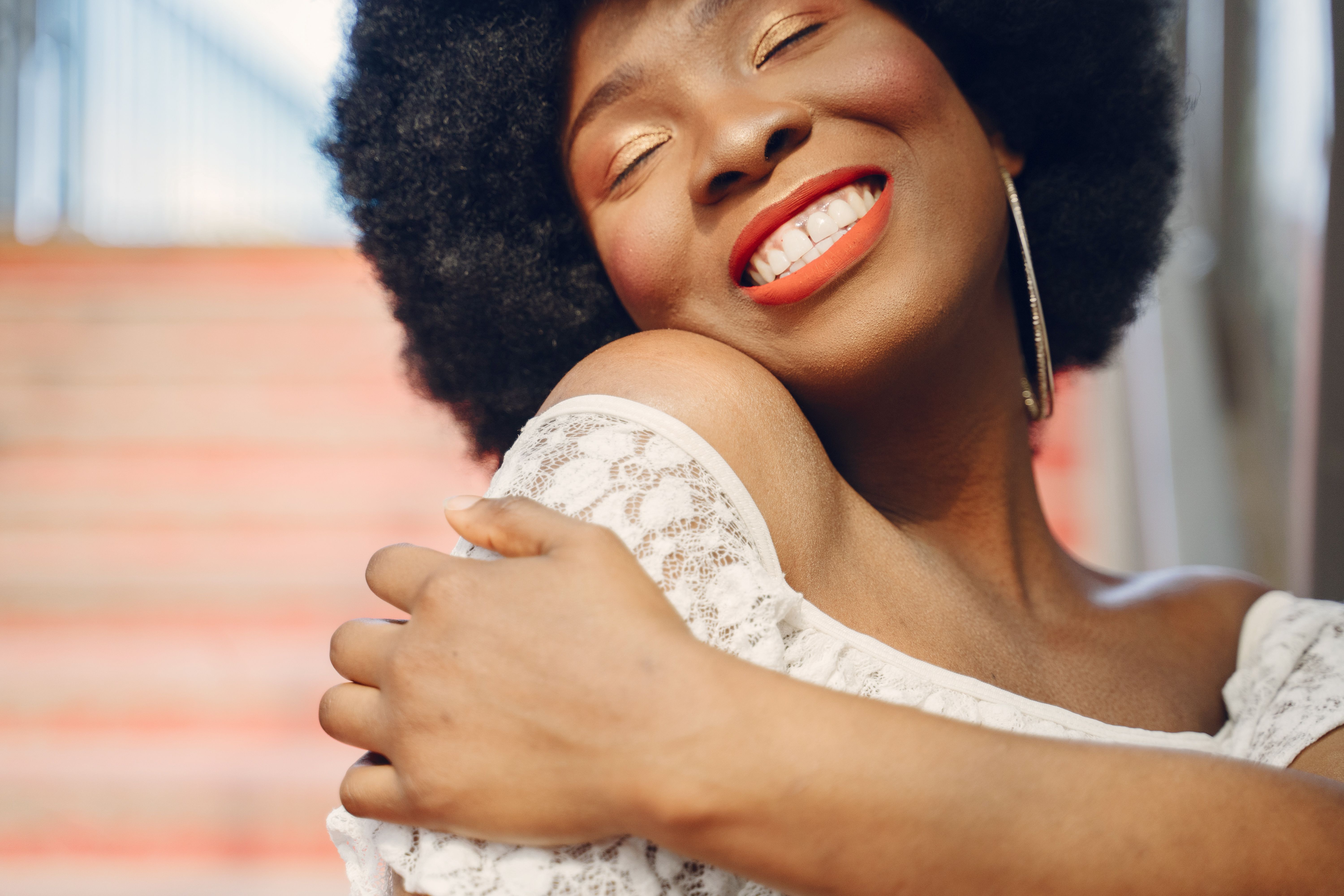 A Black woman with an afro who has learned to trust herself and is smiling with joy