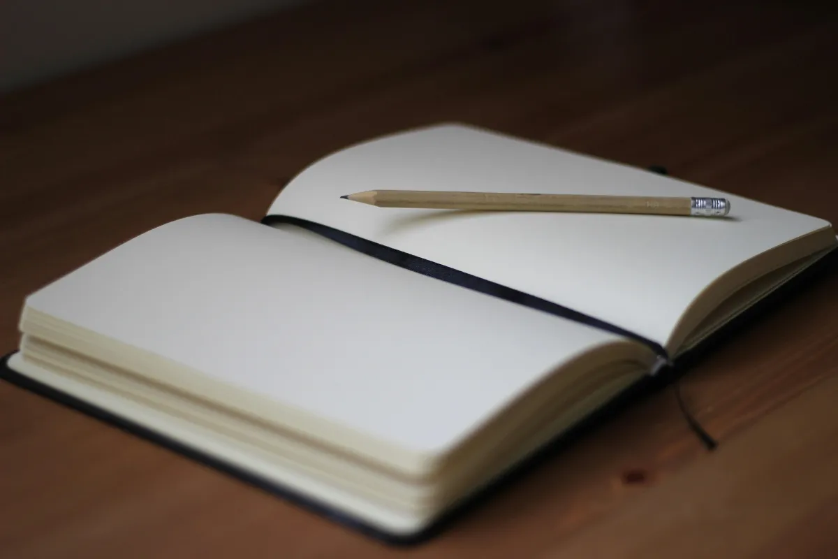An open journal sits on a wooden desk alongside a steaming cup of coffee, bathed in soft morning light, symbolizing mental clarity and focus. This serene scene encourages mindfulness and self-awareness, offering a moment to regain control over negative thoughts and manage overthinking.