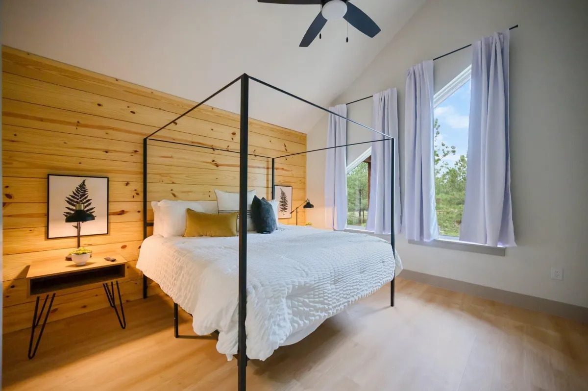 Inviting bedroom with large windows, plush bedding, and peaceful forest views.