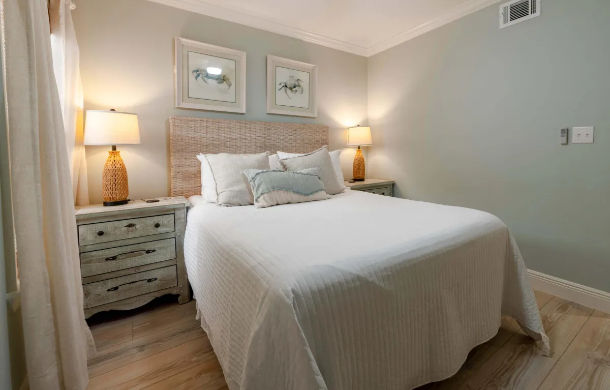 Elegant bedroom with a large bed, two lamps, and framed art above the headboard.