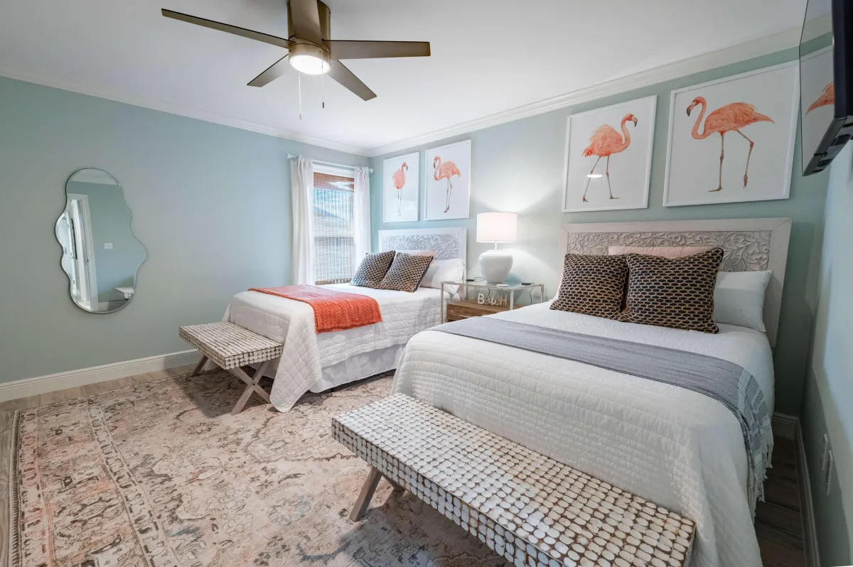 Cozy twin bedroom with flamingo art, beach vibes, and elegant white bedding.