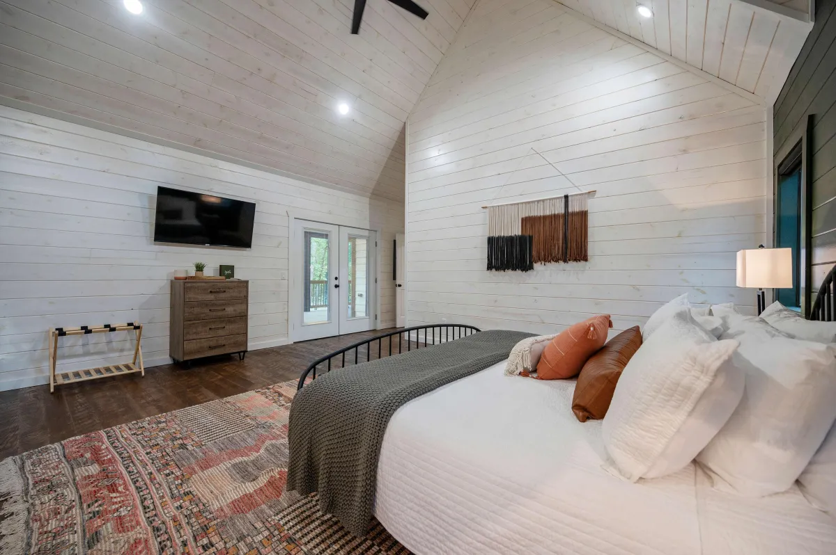 Inviting bedroom with large windows, plush bedding, and peaceful forest views.
