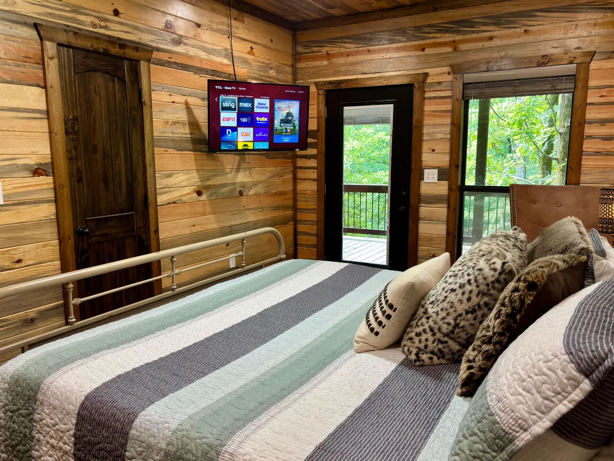 Inviting bedroom with large windows, plush bedding, and peaceful forest views.