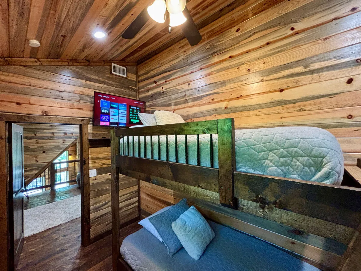 Rustic bedroom with bunk beds, wood ceiling, modern accents, and serene vibes.