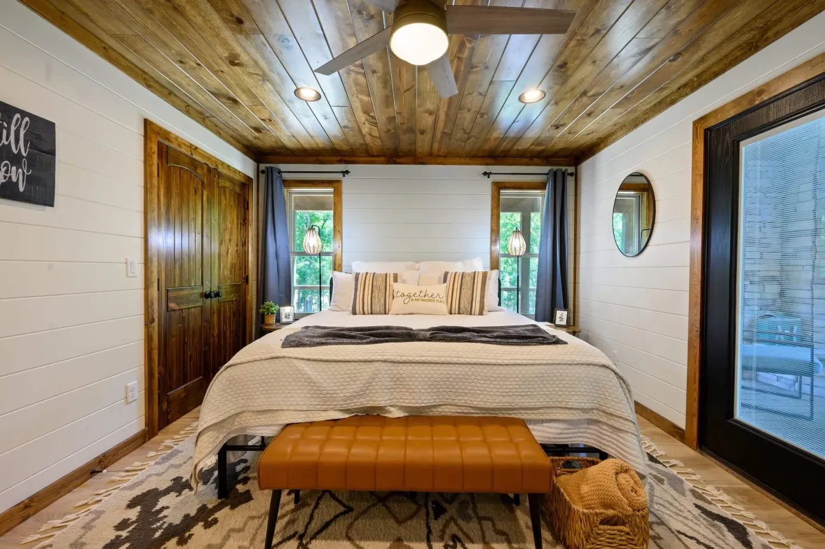 Inviting bedroom with large windows, plush bedding, and peaceful forest views.