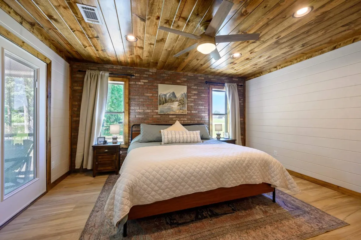 Rustic bedroom with bunk beds, wood ceiling, modern accents, and serene vibes.