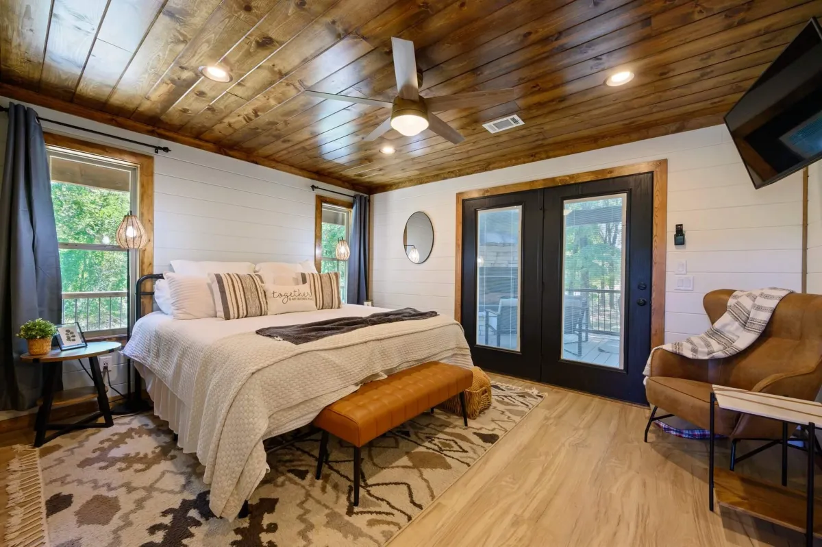 Inviting bedroom with large windows, plush bedding, and peaceful forest views.