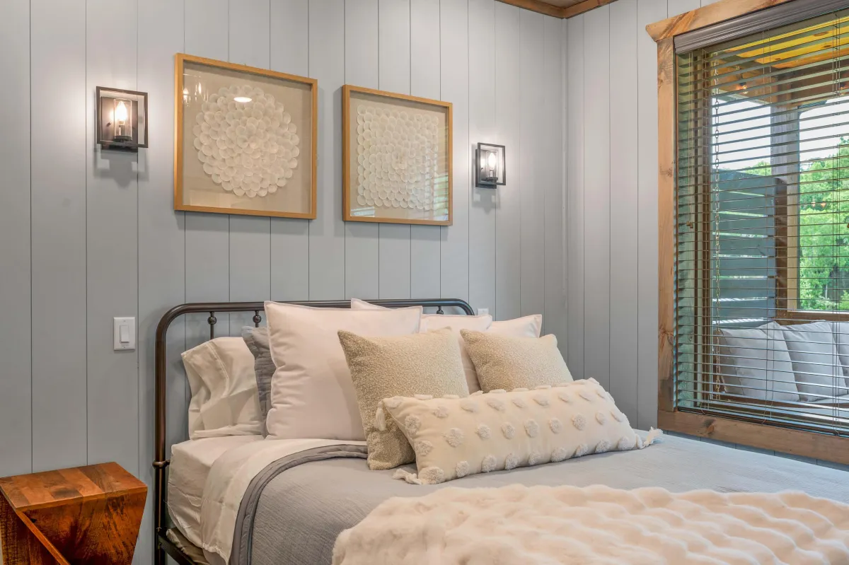 Inviting bedroom with large windows, plush bedding, and peaceful forest views.
