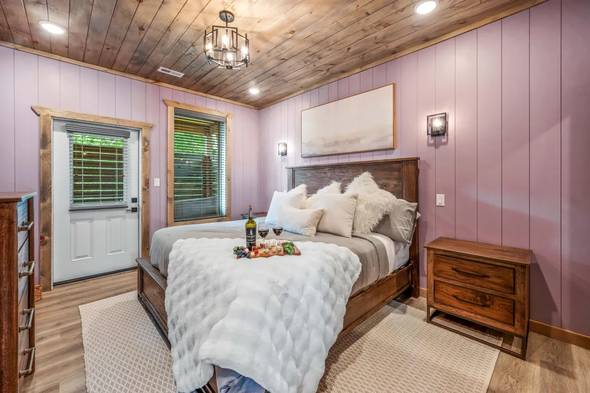 Inviting bedroom with large windows, plush bedding, and peaceful forest views.