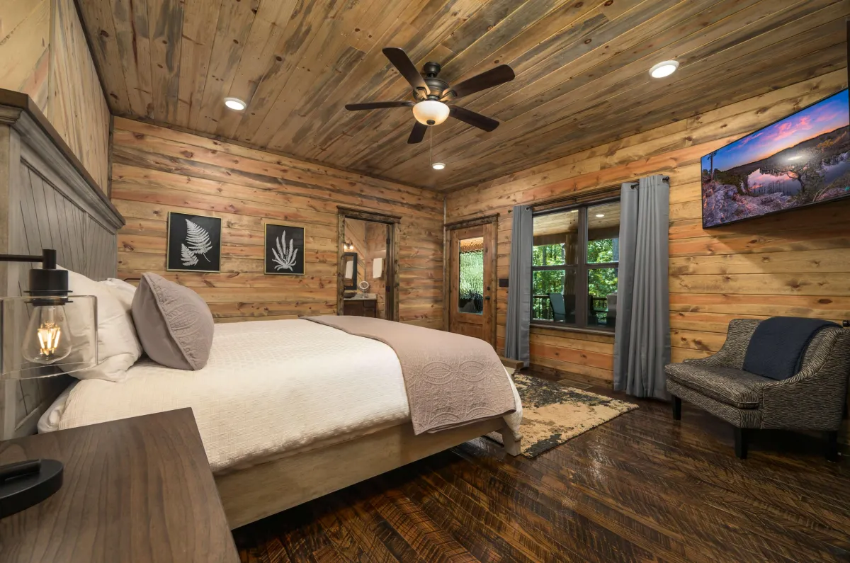 Inviting bedroom with large windows, plush bedding, and peaceful forest views.