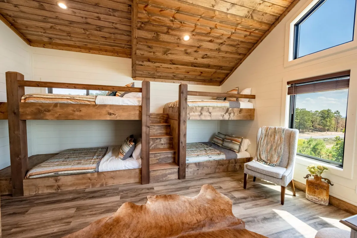 Rustic bedroom with bunk beds, wood ceiling, modern accents, and serene vibes.