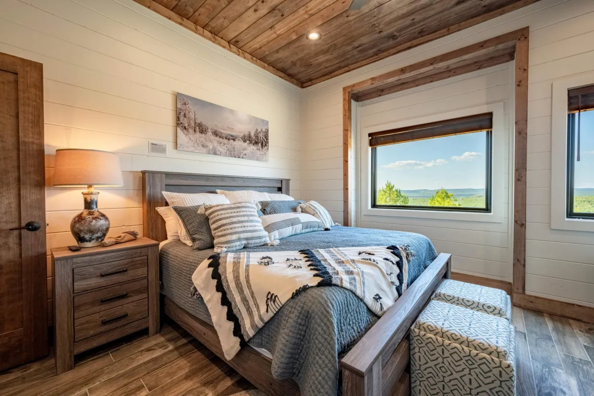 Inviting bedroom with large windows, plush bedding, and peaceful forest views.