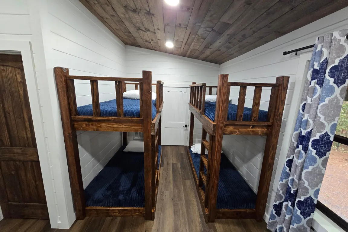 Charming loft bedroom with wooden ceilings, cozy beds, and rustic decor.