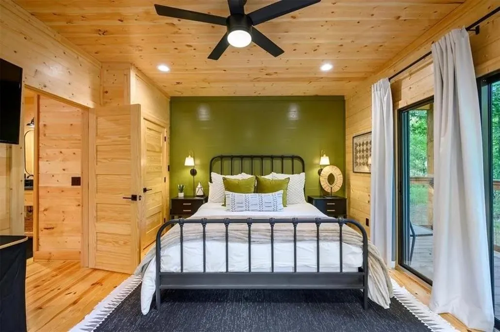 Inviting bedroom with large windows, plush bedding, and peaceful forest views.