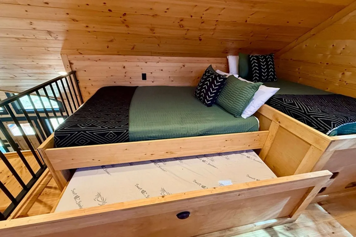 Charming loft bedroom with wooden ceilings, cozy beds, and rustic decor.
