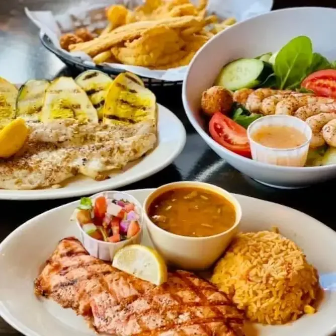 Grilled fish paired with rice, salad, soup, and fried side dishes.