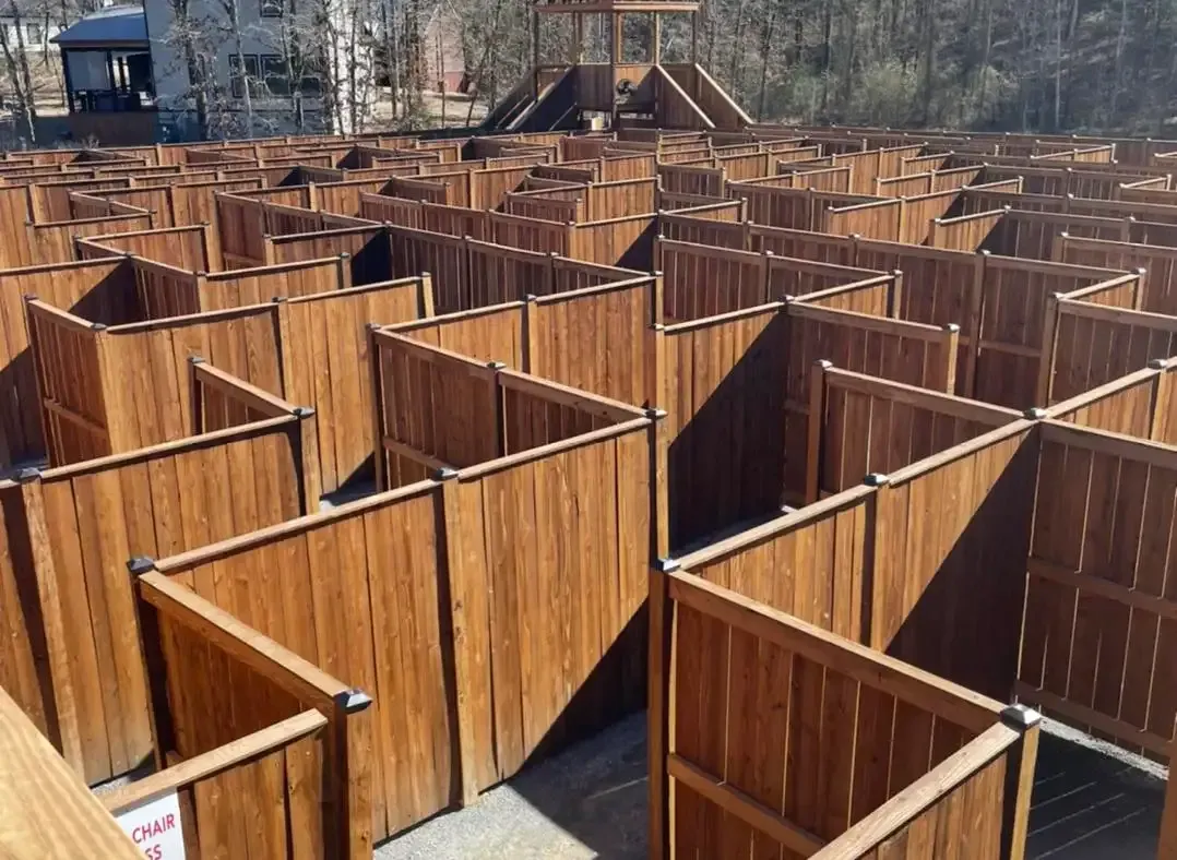 Large wooden maze with pathways and central observation tower outdoors.