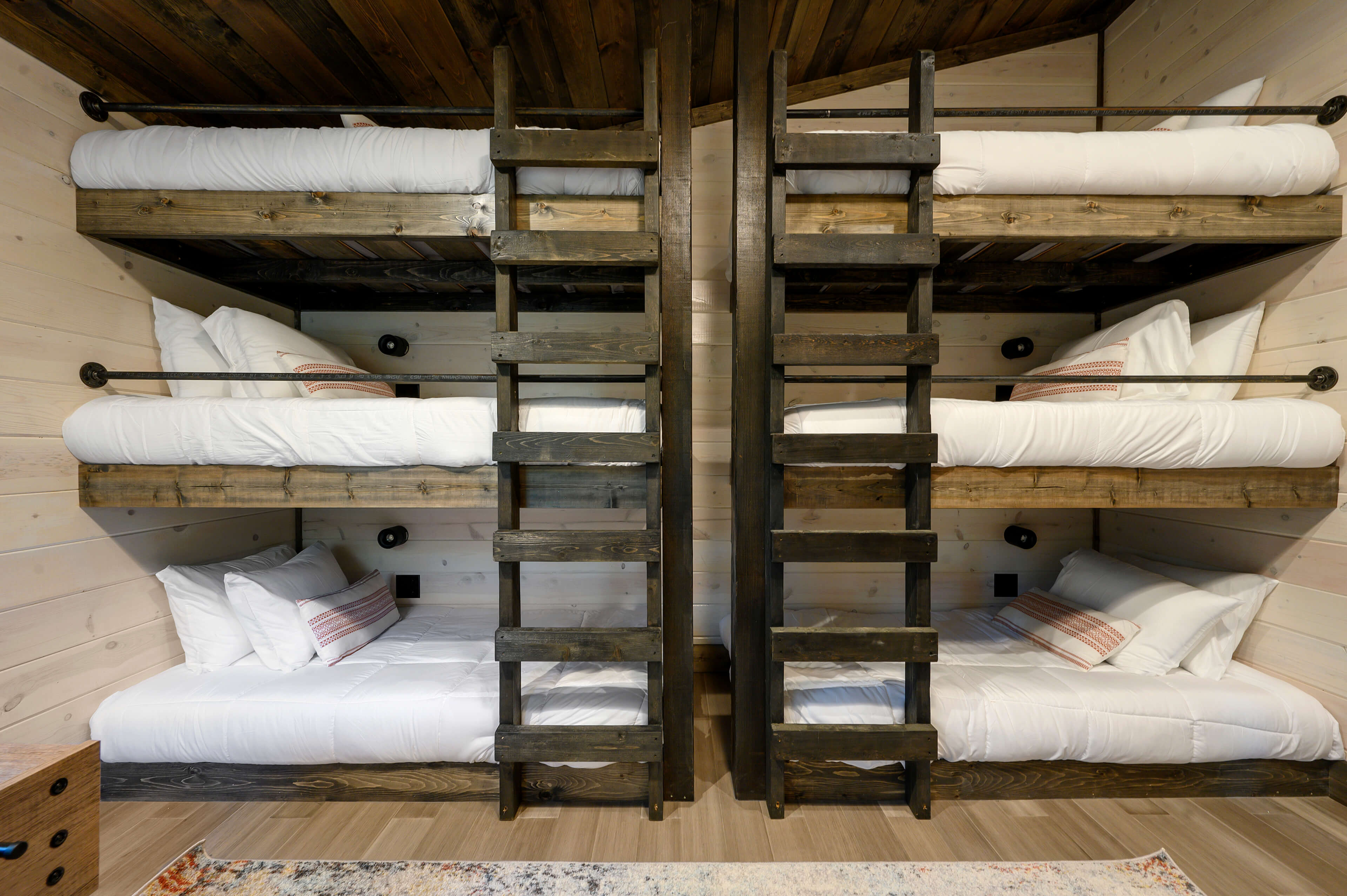Warm bunk bedroom with wood walls, cozy lighting, and vibrant bedding.