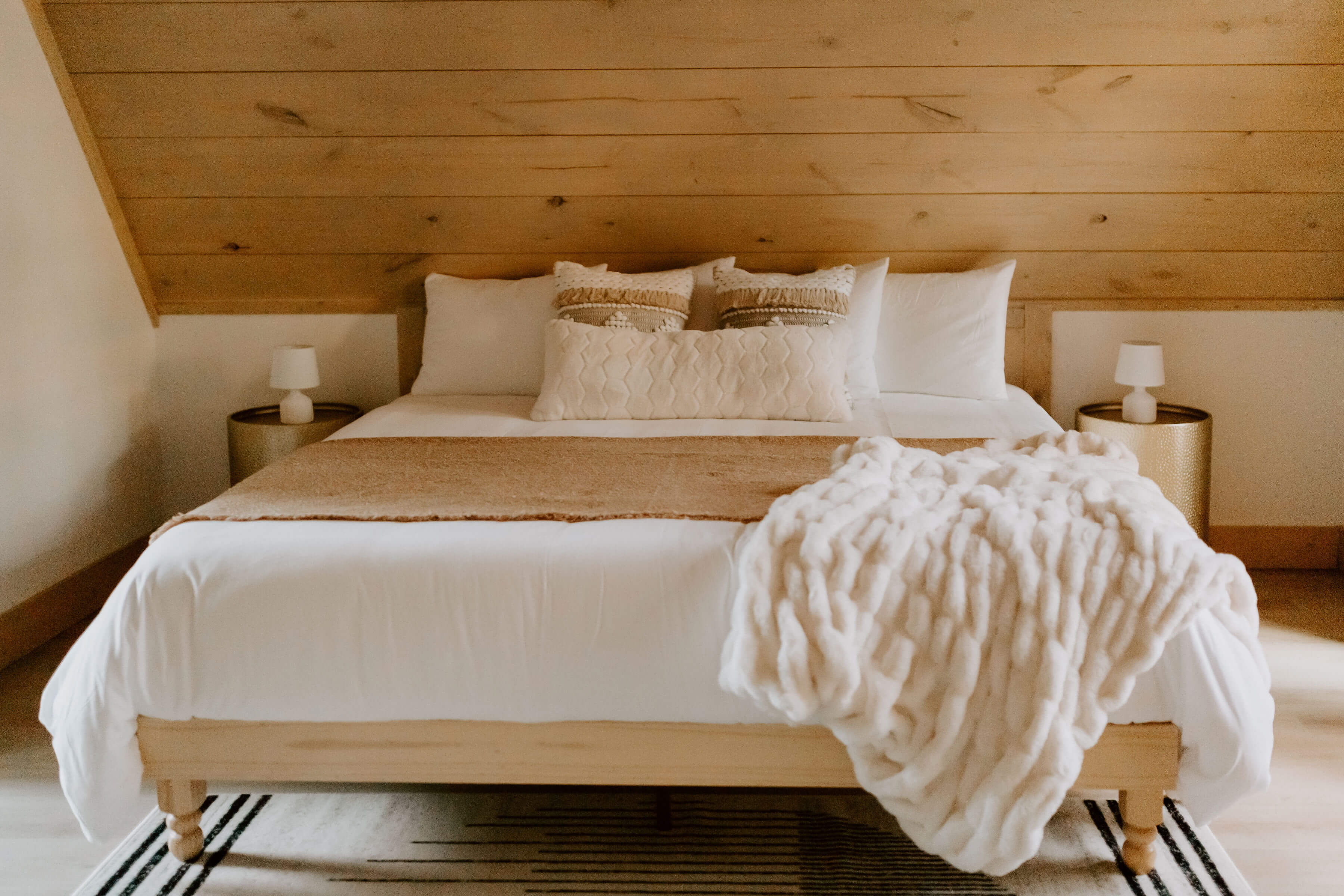 Rustic bedroom with wooden ceiling, blue accents, and large windows to nature.