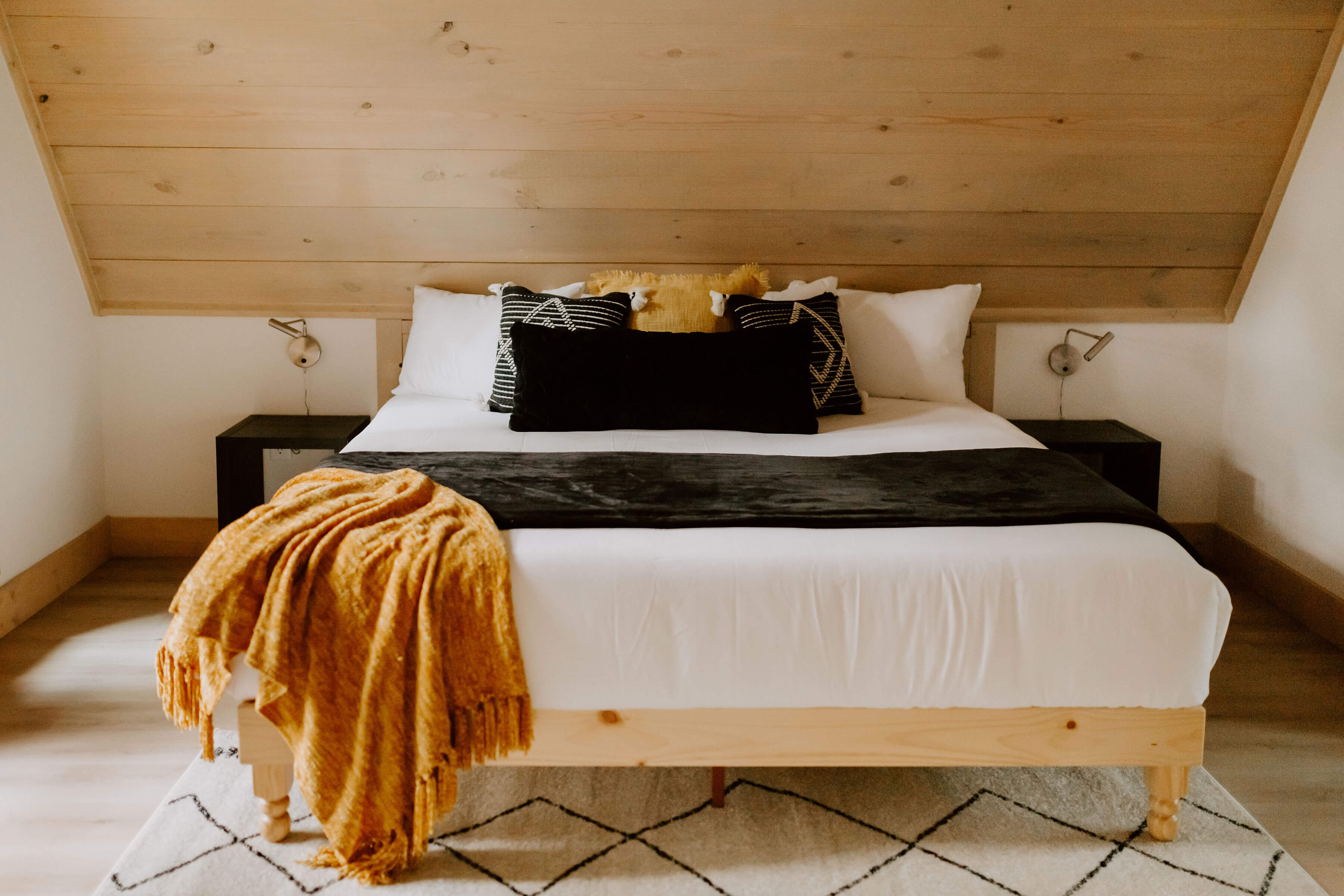 Modern cabin bedroom with white bunk beds, wood walls, and cozy blue decor.