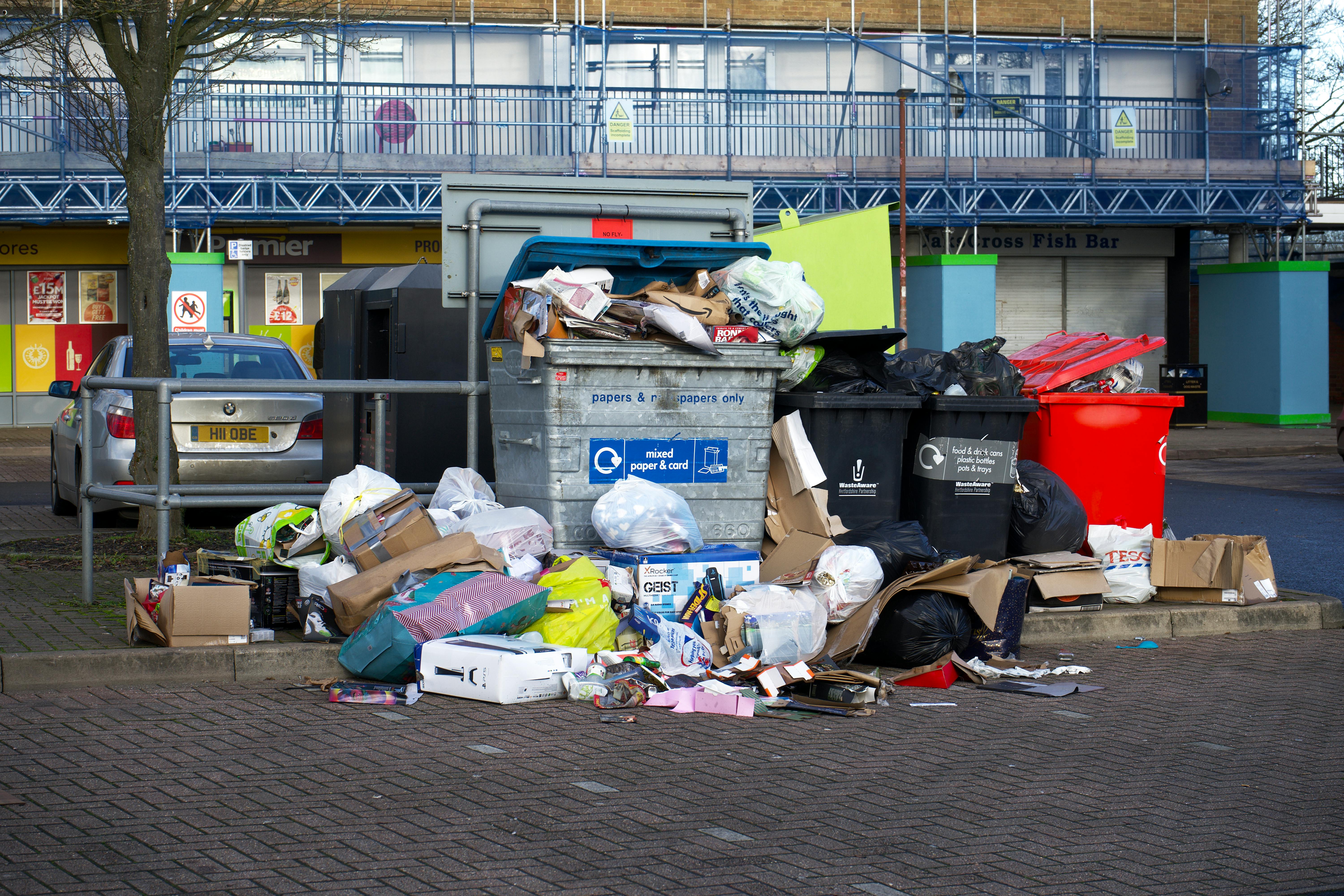 red and black bins along with silver bin and plastic bags thrown around
