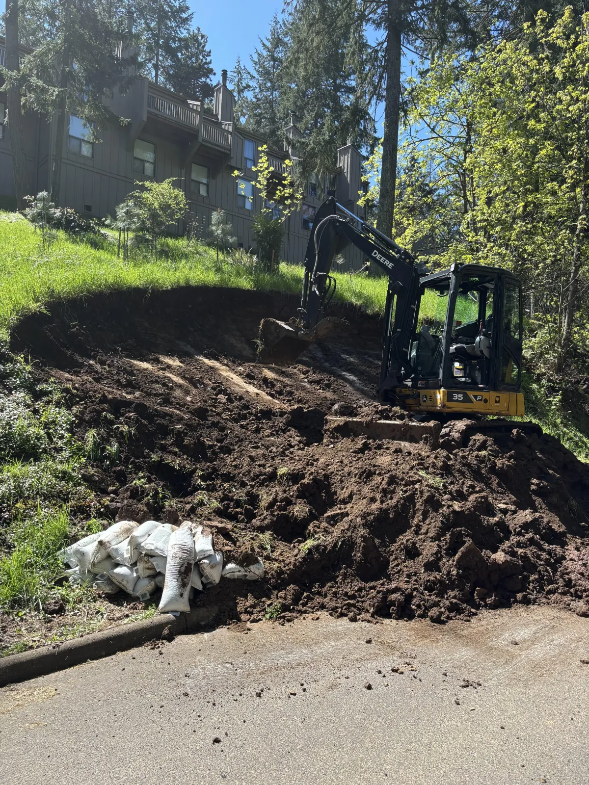 Excavator performing slope stabilization and hillside grading after landslide in South Eugene Hills, Oregon