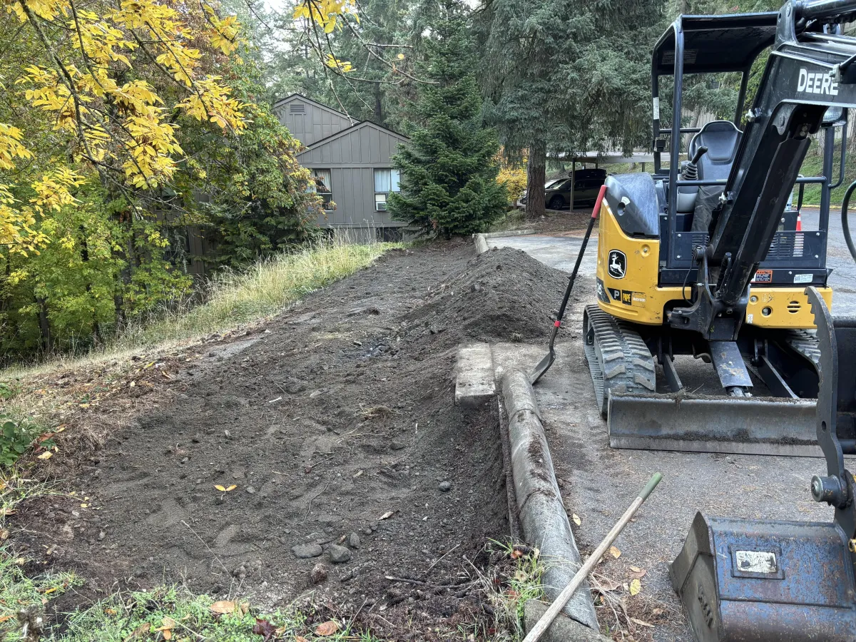Landslide cleanup and final slope grading using excavator along roadway in the South Eugene Hills, Oregon