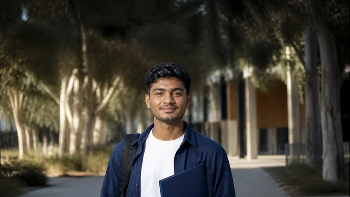 A student with a backpack and navy folder smiles at the camera on a eucalyptus-lined path beside a modern building on an Australian campus, exploring Deakin University.