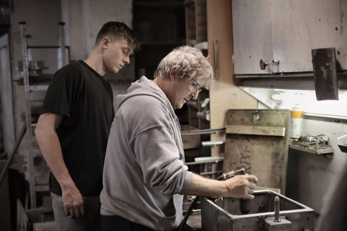Teen learning a trade alongside an adult mentor