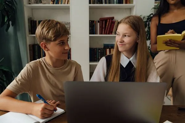 Two teens talking over notes at a desk