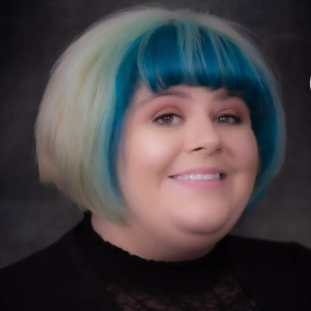 Stylist Jen smiling in a light, feminine salon