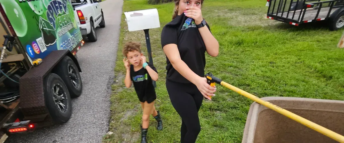 Kids reacting to the smell of a dirty trash bin beside a cleaning service truck in Cape Coral.