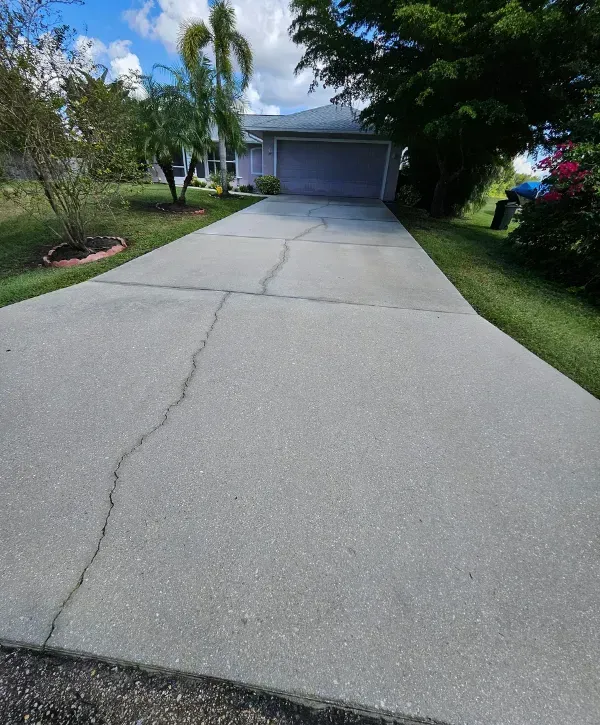 A long residential driveway in Cape Coral showing light surface dirt before pressure washing.