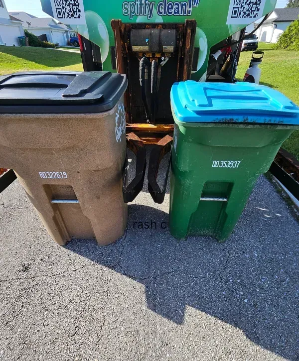 Two trash bins positioned in front of a cleaning truck for service