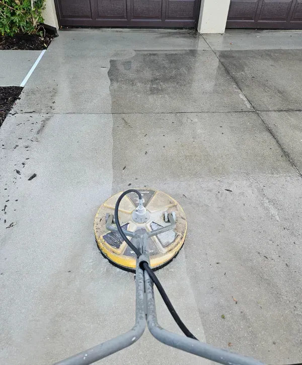 Surface cleaner pressure washing a concrete driveway with a clear before-and-after result