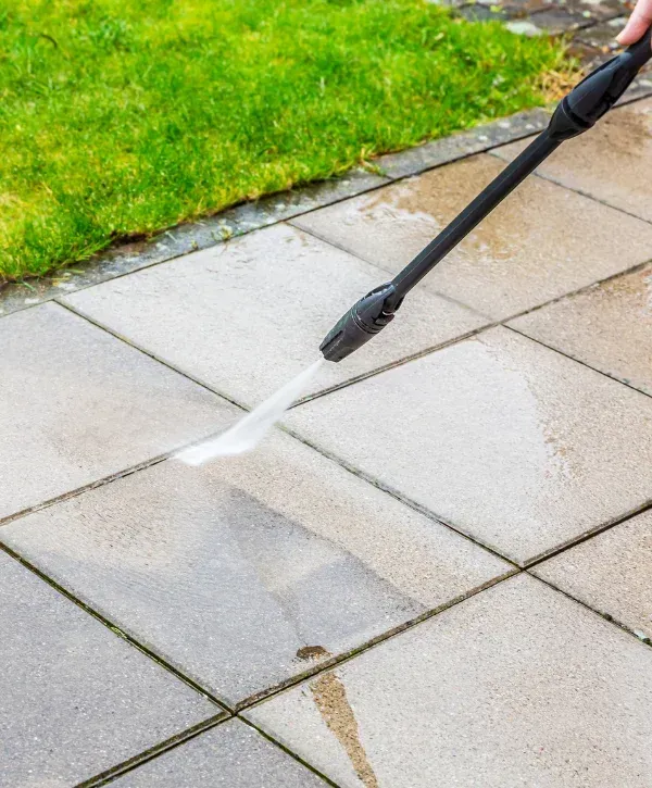 Pressure washing patio pavers to remove dirt, algae, and stains