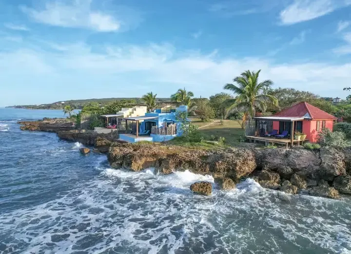 Coastal view of vibrant blue and red beach houses on rocky cliffs