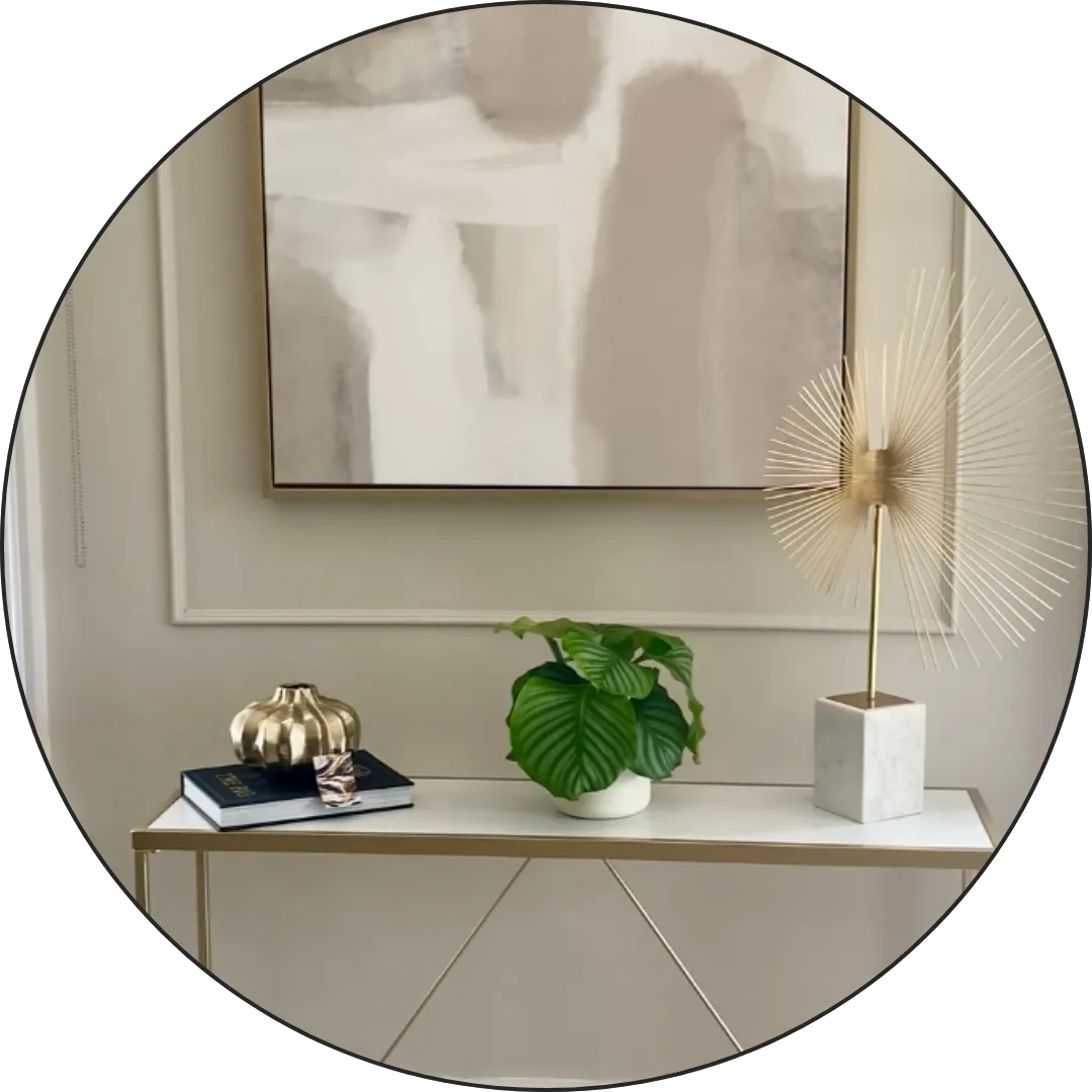Picture of white and gold console table with plant and artwork 
